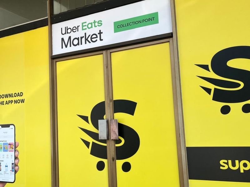 Commercial storefront entrance featuring double glass doors with metal framing and prominent branding signage.