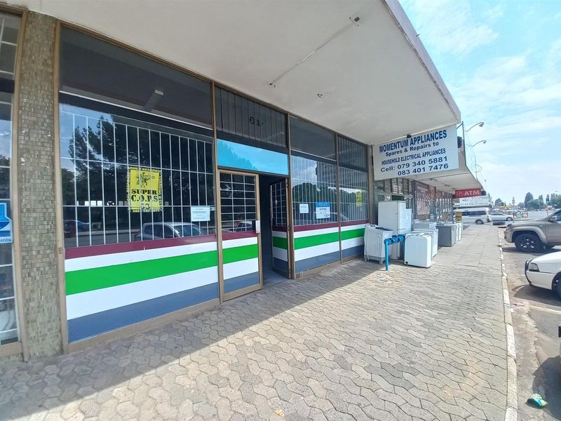 Commercial shopfront with large display windows, security gates, and a paved sidewalk area, featuring prominent signage for an appliance repair business.