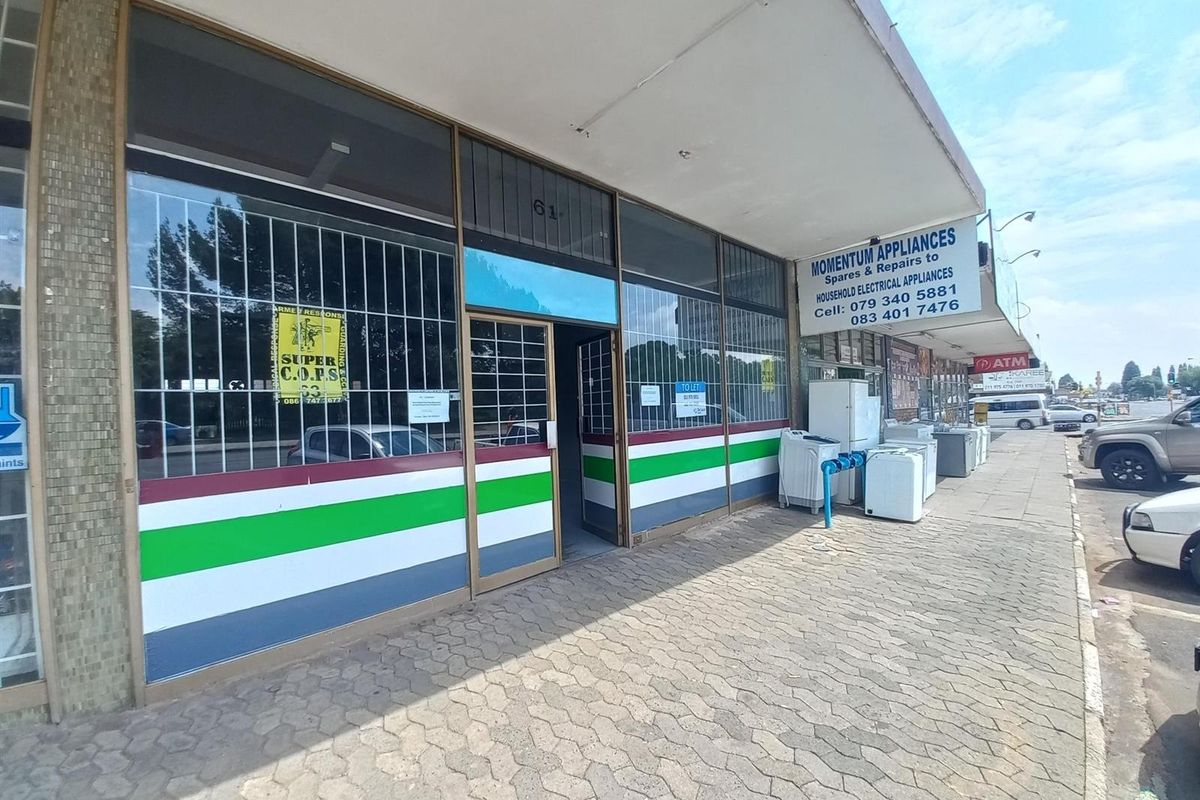 Commercial shopfront with large display windows, security gates, and a paved sidewalk area, featuring prominent signage for an appliance repair business.