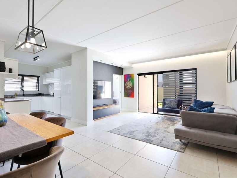 Modern open-plan living area featuring tiled floors, sleek kitchen cabinetry, recessed lighting, and seamless access to an outdoor patio through sliding glass doors.