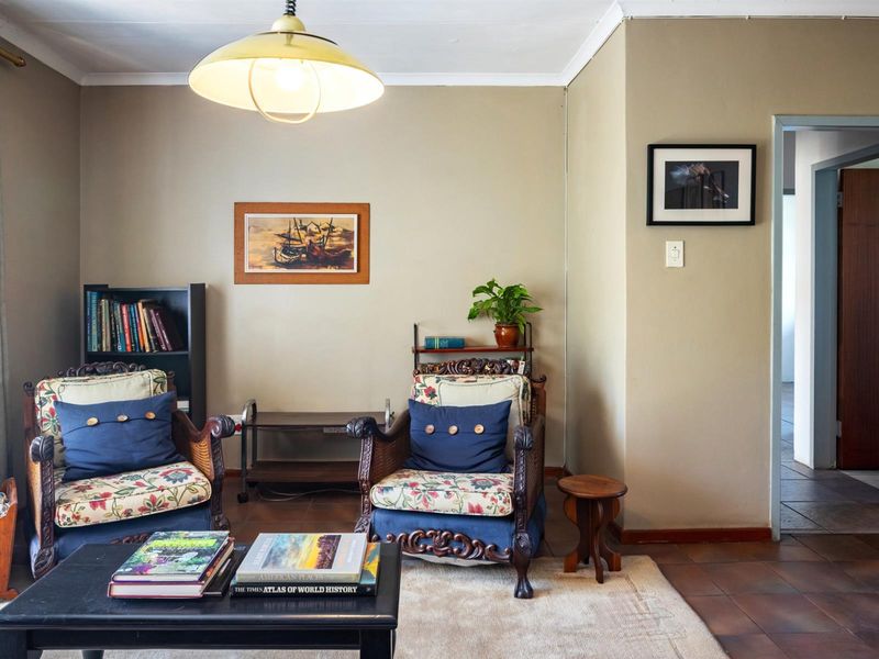 A cozy living room featuring tiled flooring, neutral wall tones, and a central pendant light fixture, providing a comfortable and functional living space.