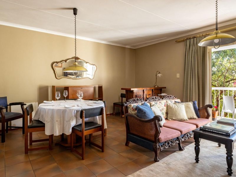 Open-plan living and dining area featuring tiled flooring, pendant lighting, and direct access to a private balcony through sliding glass doors.