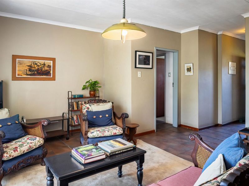 A living room featuring tiled flooring and a central pendant light fixture, providing a functional and traditional living space.