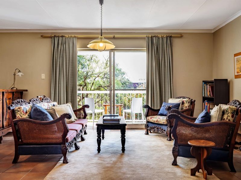 A comfortable living room featuring tiled flooring, a central pendant light, and sliding glass doors that open onto a private balcony.