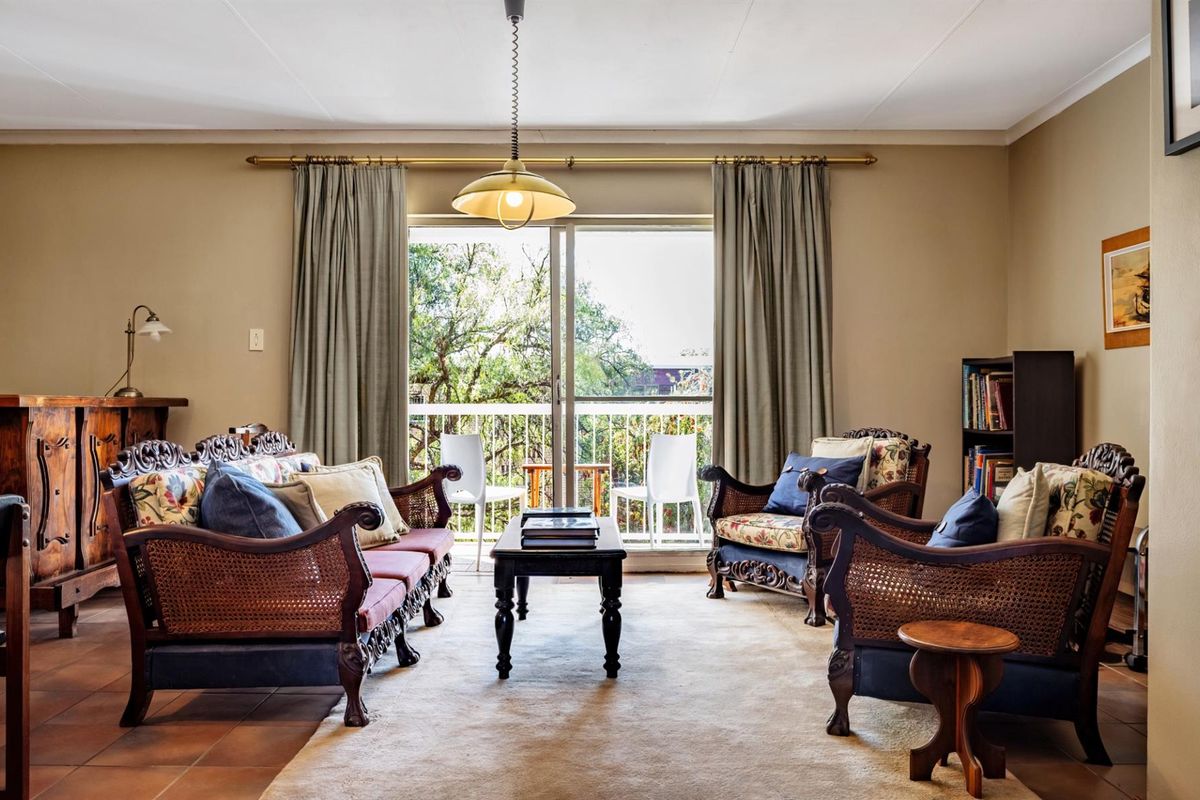 A comfortable living room featuring tiled flooring, a central pendant light, and sliding glass doors that open onto a private balcony.