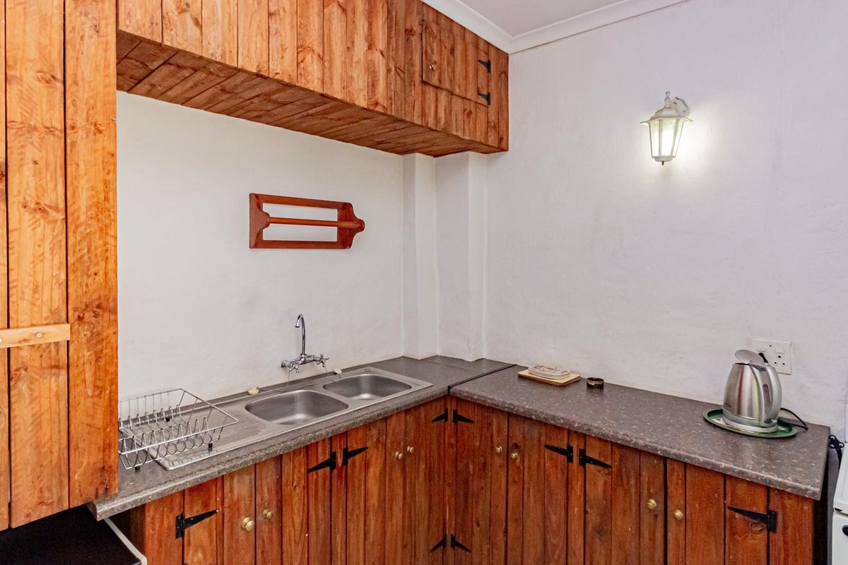 A compact kitchen area featuring rustic timber cabinetry, a double-basin stainless steel sink, and laminate countertops.