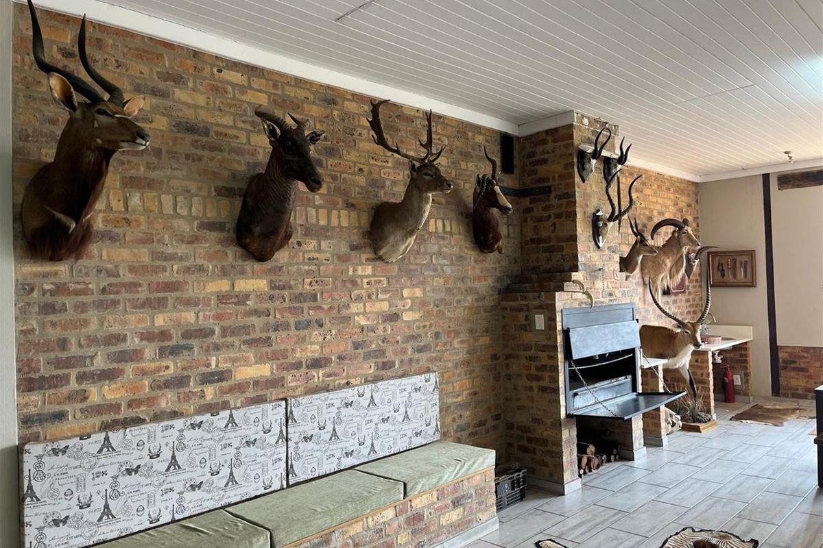 Spacious living area featuring a prominent exposed brick wall, built-in fireplace, and tiled flooring, offering a rustic farm-style aesthetic.