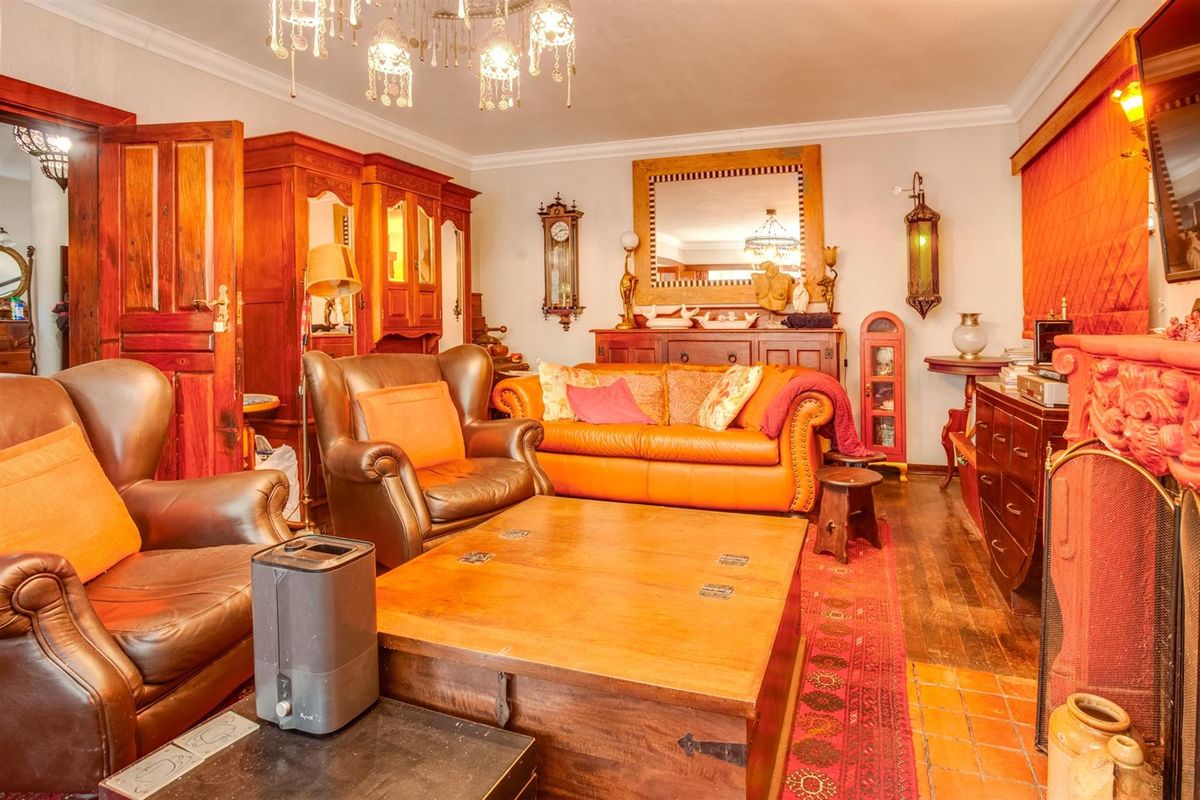 A traditional living room featuring warm timber flooring, a decorative fireplace surround, and classic crown molding, creating a cozy and inviting atmosphere.