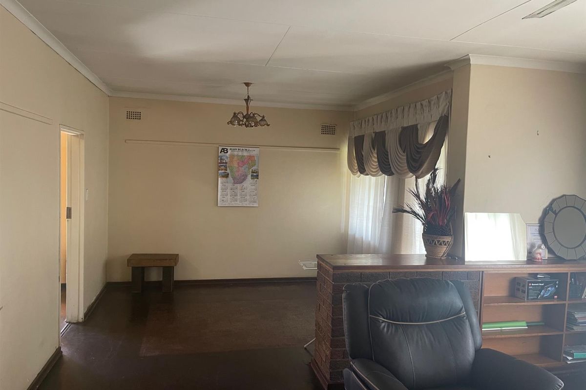 A spacious living area featuring a brick room divider, dark flooring, and neutral walls, offering a versatile layout for comfortable family living.