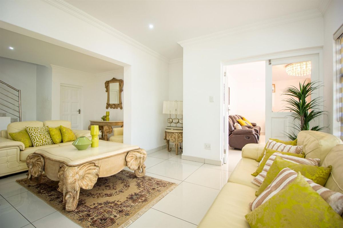 Spacious living area featuring large format floor tiles, recessed ceiling lighting, and a seamless transition into an adjacent room through a wide opening.
