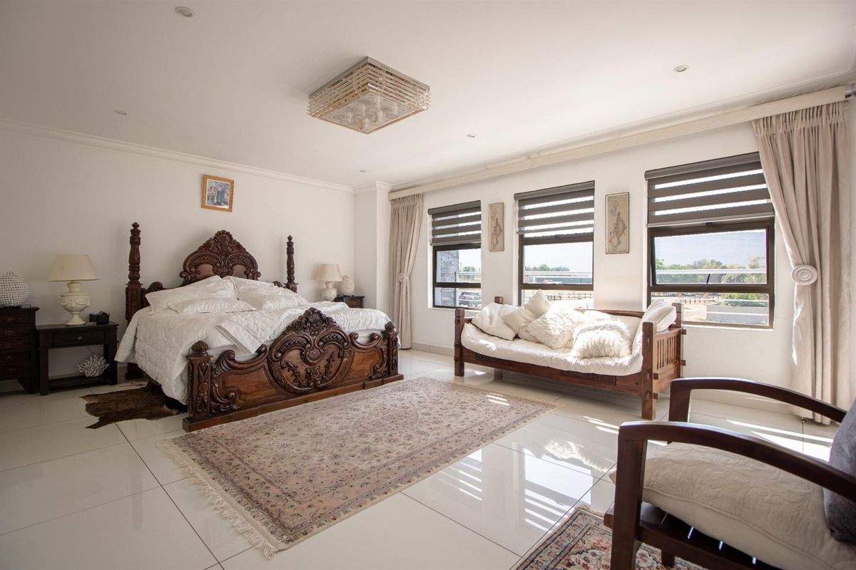 Spacious bedroom featuring large format floor tiles, recessed downlighting, and multiple windows with fitted blinds, offering a bright and airy living space.