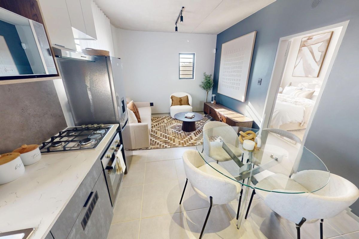 Modern open-plan living area featuring a compact kitchen with gas hob, oven, and tiled flooring, seamlessly flowing into the dining and lounge space.