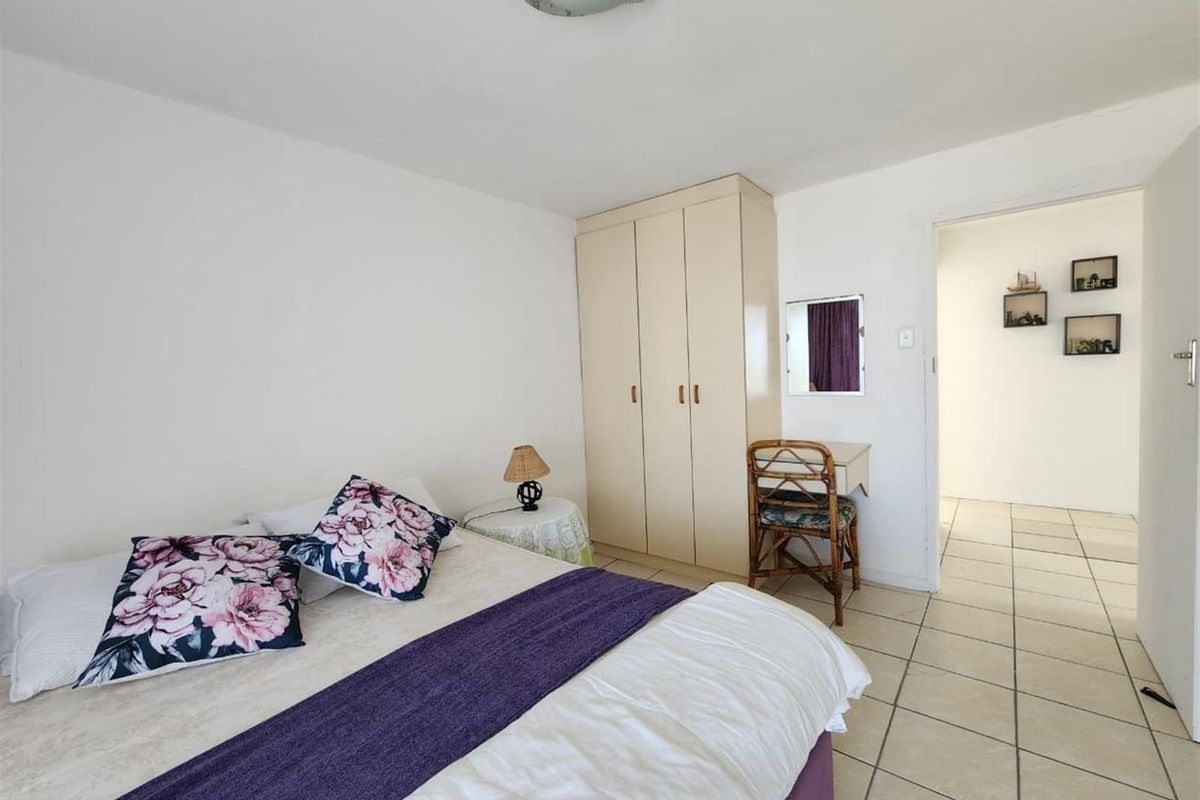 A functional bedroom featuring neutral tiled flooring and a built-in wardrobe, offering a clean and simple space ready for personalization.
