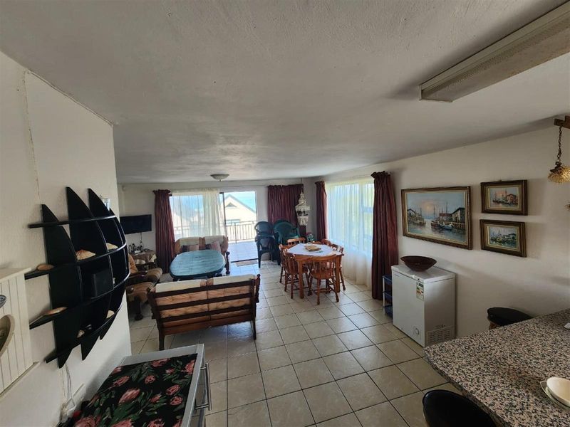 Spacious open-plan living and dining area featuring tiled flooring, a granite breakfast counter, and direct access to a balcony with scenic views.