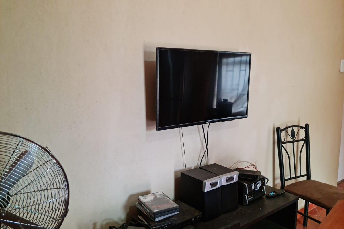 A living area featuring a wall-mounted television and neutral wall finishes.