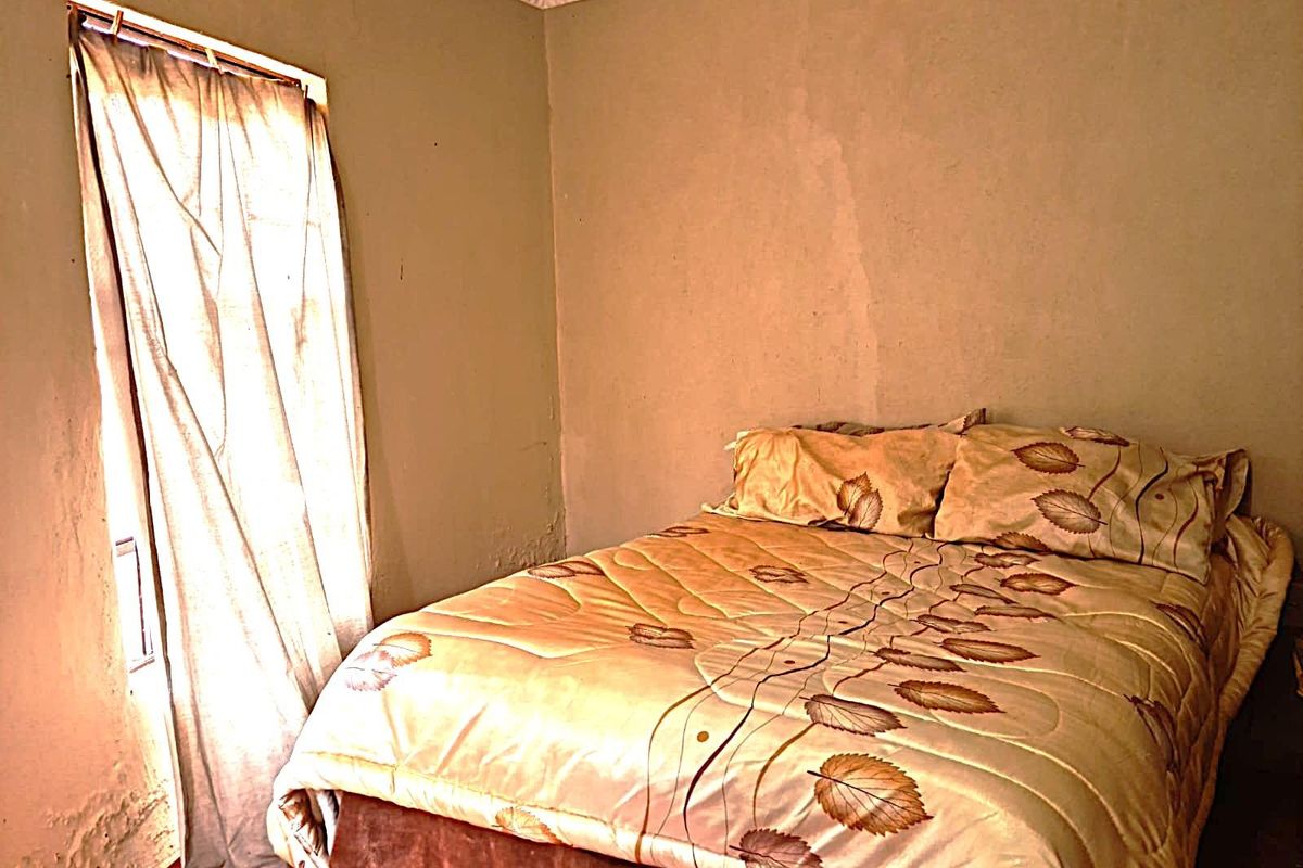A bedroom featuring basic finishes with visible wall surface deterioration and signs of moisture or wear.