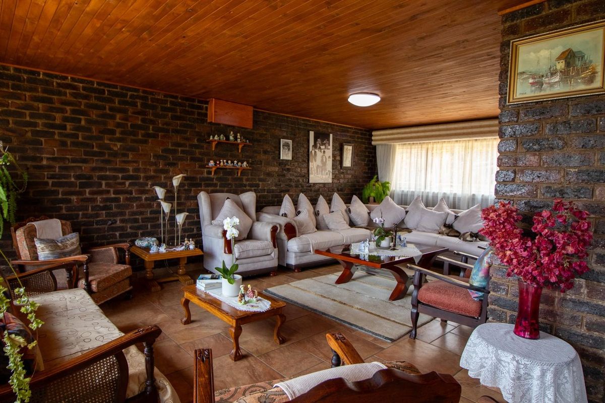 Spacious living room featuring exposed dark brick walls, a warm timber-paneled ceiling, and tiled flooring, creating a rustic and cozy atmosphere.
