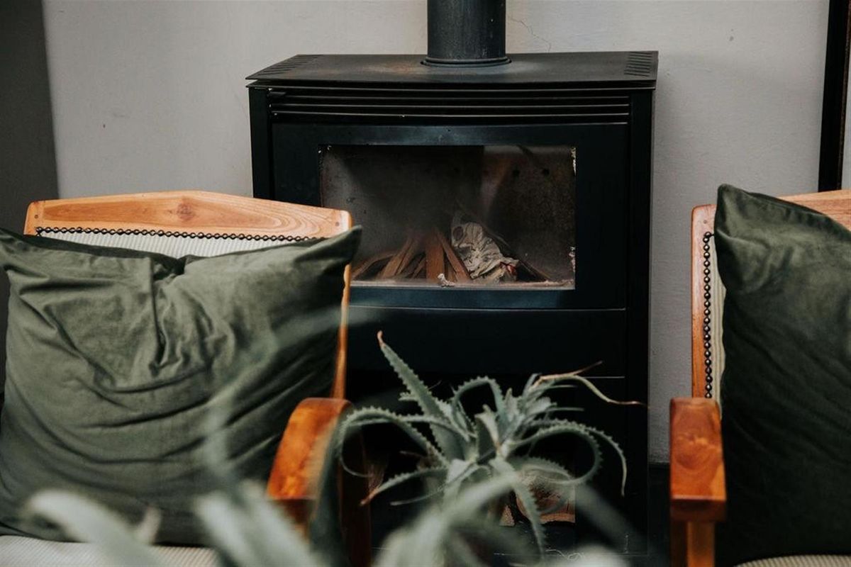 A cozy living area featuring a black metal wood-burning fireplace as a central focal point.