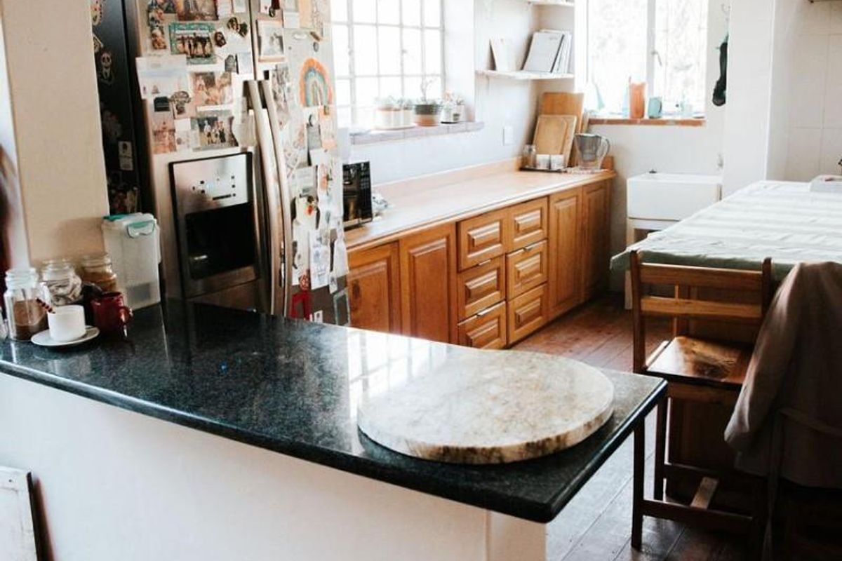 A functional kitchen featuring wooden cabinetry, a dark granite breakfast bar, and timber flooring, offering a classic and practical layout.