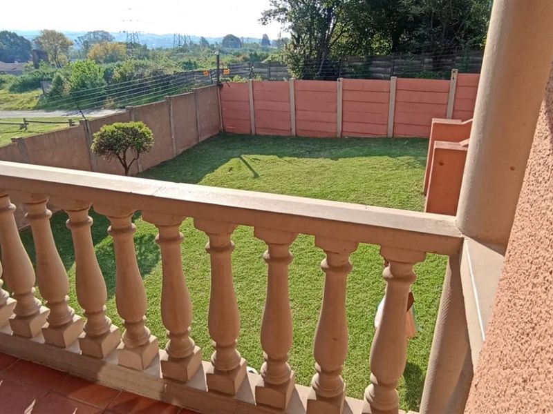 Elevated balcony featuring a classic concrete balustrade, overlooking a private rear garden enclosed by precast concrete boundary walls.