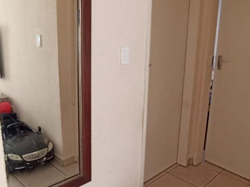 A functional hallway featuring neutral tiled flooring and access to multiple internal rooms.