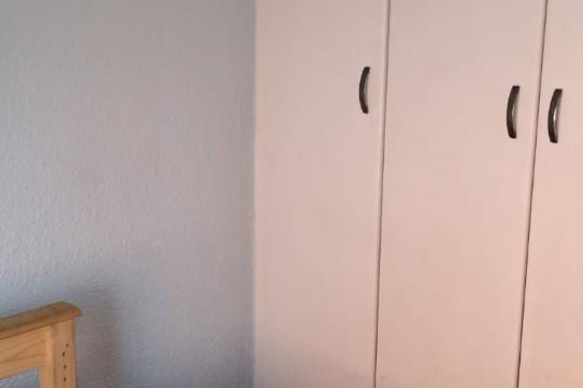 A bedroom featuring a built-in wardrobe with white doors and light blue wall finishes.