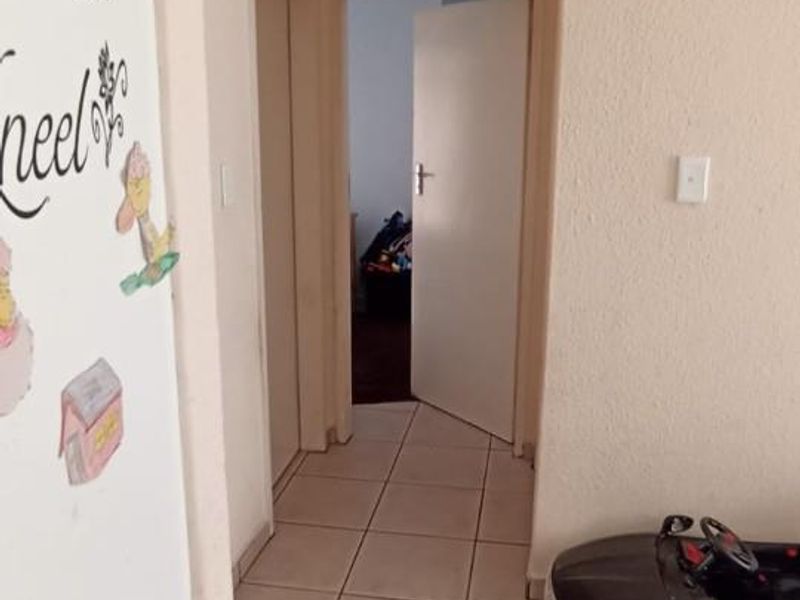 A functional hallway featuring neutral tiled flooring and access to adjacent rooms through internal doors.