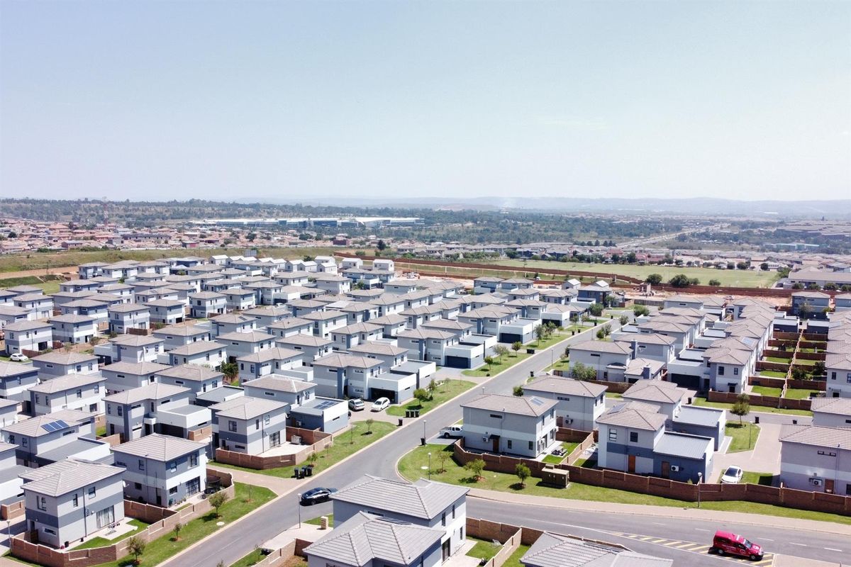 An aerial view of a modern residential estate featuring uniform detached houses with tiled roofs and paved driveways.