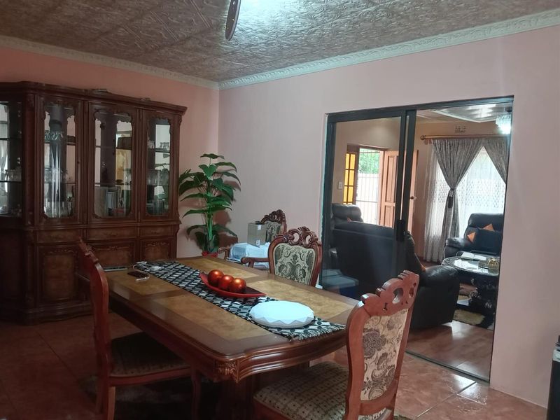 A formal dining room featuring tiled flooring and a decorative ceiling, with sliding glass doors providing access to an adjacent living area.
