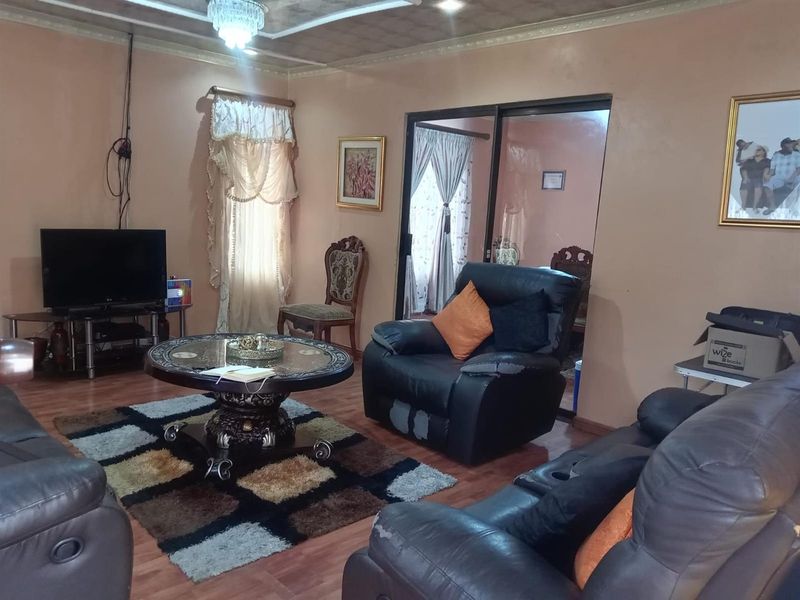A living room featuring laminate flooring, a decorative ceiling, and sliding glass doors leading to an adjacent space.