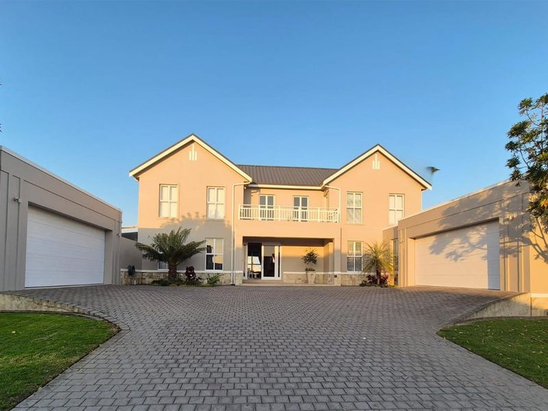A well-maintained double-story residence featuring a paved driveway, two double garages, and a balcony overlooking the front entrance.