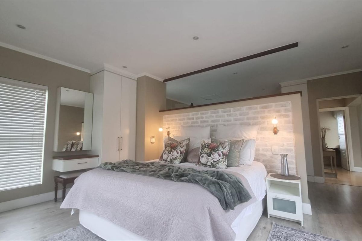 Spacious bedroom featuring a built-in wardrobe, vanity area, and a decorative brick-style feature wall behind the bed.