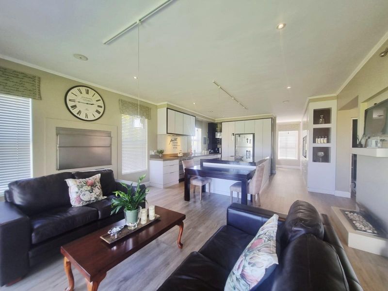 Spacious open-plan living area featuring a modern kitchen with integrated cabinetry, a central island, and a comfortable lounge space with a fireplace.