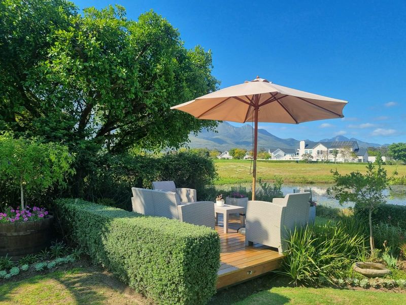 A tranquil garden setting featuring a timber deck overlooking a pond with scenic mountain views.