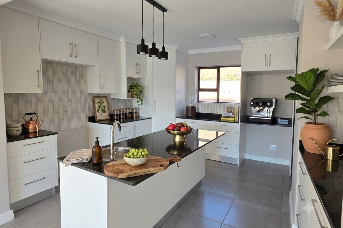 Modern kitchen featuring a central island with granite countertops, sleek white cabinetry, tiled backsplash, and contemporary pendant lighting.