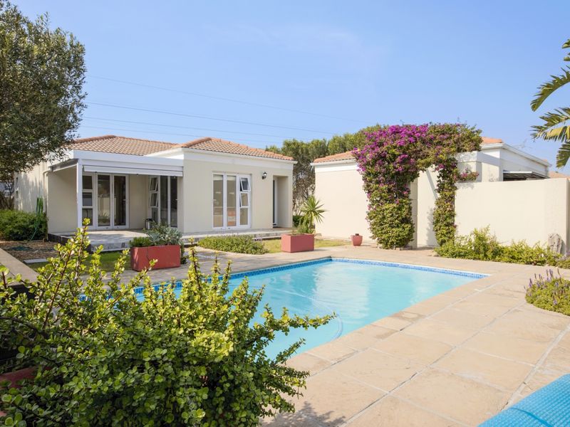 A well-maintained outdoor pool area featuring a tiled deck, a swimming pool, and direct access to the residence via sliding glass doors.