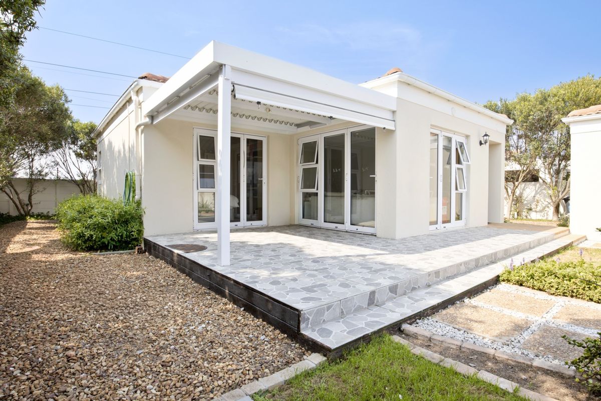 A well-maintained rear exterior featuring a covered patio with tiled flooring, pergola structure, and multiple aluminium-framed glass doors providing access to the home.