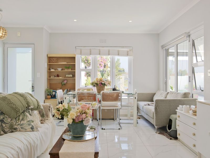 Bright open-plan living and dining area featuring polished tiled floors, recessed lighting, and large glass doors providing ample natural light.