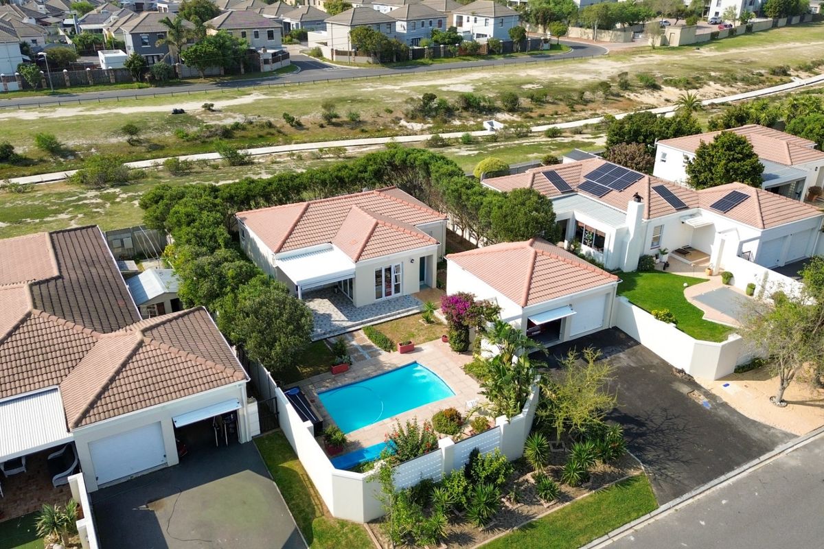 Aerial view of a residential property featuring a swimming pool, tiled roof, solar panels, and a private driveway within a suburban estate.