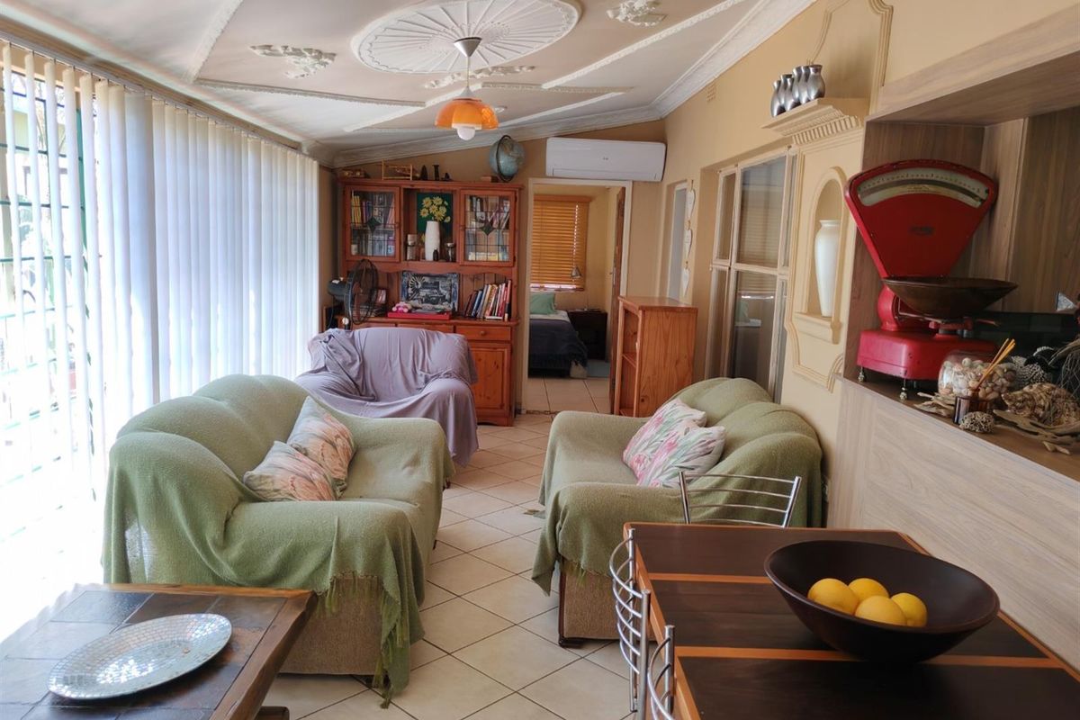 A spacious living area featuring decorative ceiling cornices, tiled flooring, and a wall-mounted air conditioning unit, providing a comfortable and functional living space.