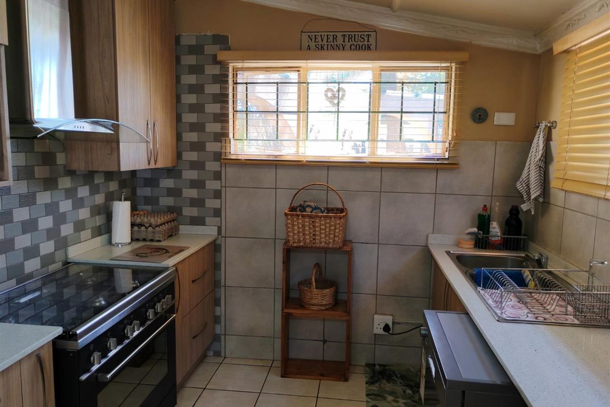Functional kitchen featuring wood-look cabinetry, tiled splashbacks, a built-in oven with extractor fan, and a double sink with countertop workspace.