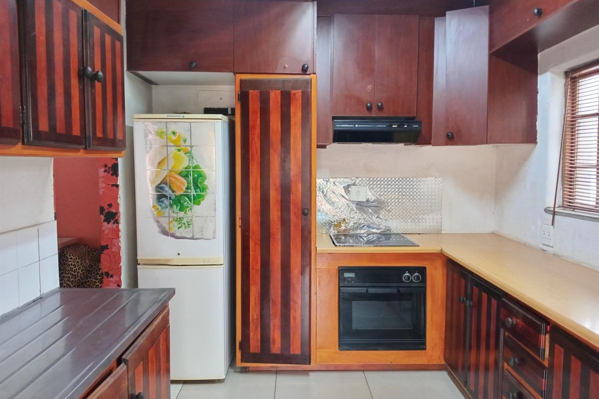 A functional kitchen featuring dark wood-toned cabinetry, built-in oven and hob, and tiled flooring, offering potential for a modern cosmetic update.