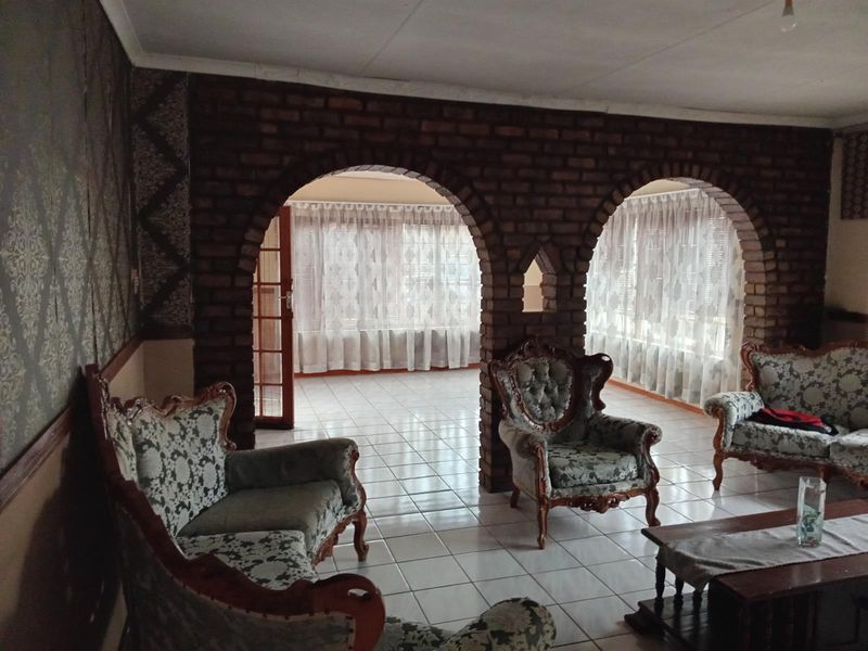 Spacious living area featuring distinctive exposed brick archways, ceramic tiled flooring, and decorative wallpaper, offering a unique architectural layout.