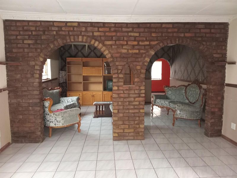 Living area featuring distinctive exposed brick archways and ceramic tiled flooring, offering a unique architectural layout with potential for modern updates.