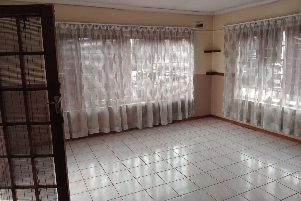 An empty living room featuring tiled flooring, timber framed door, and built-in shelving, offering a blank canvas for renovation.