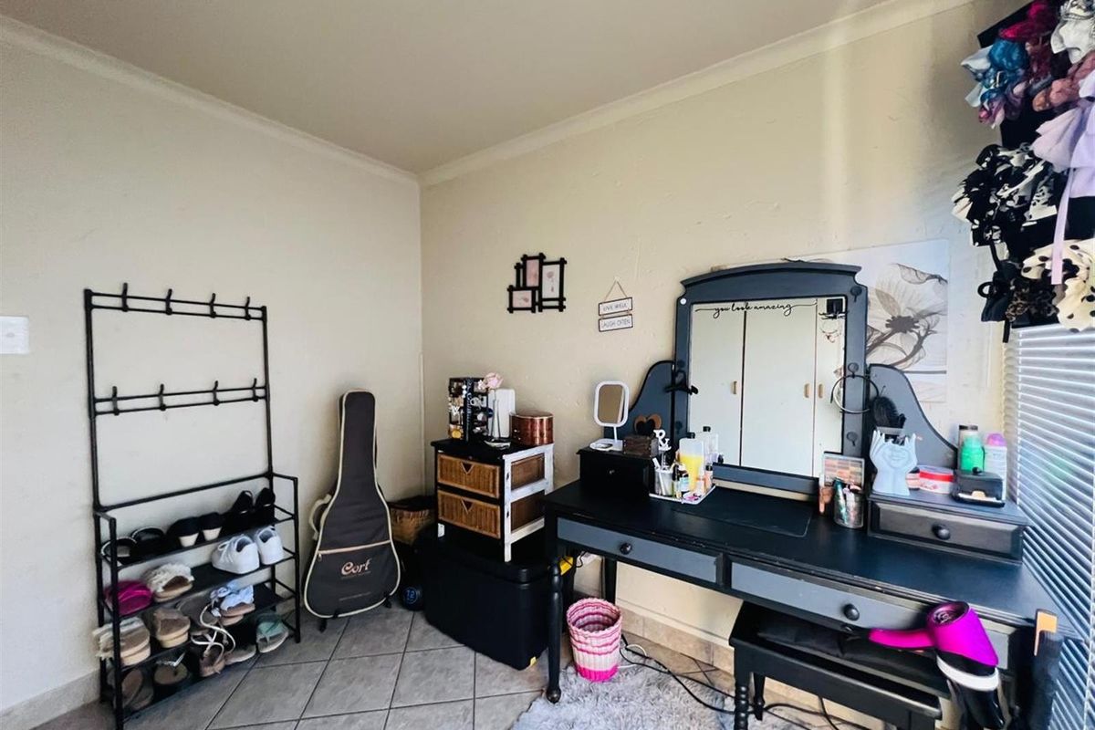 A bedroom space featuring tiled flooring and neutral wall finishes, currently utilized as a dressing area.
