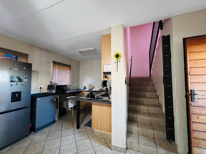 Open plan kitchen area featuring tiled flooring, built-in cabinetry, and an adjacent staircase leading to the upper level.