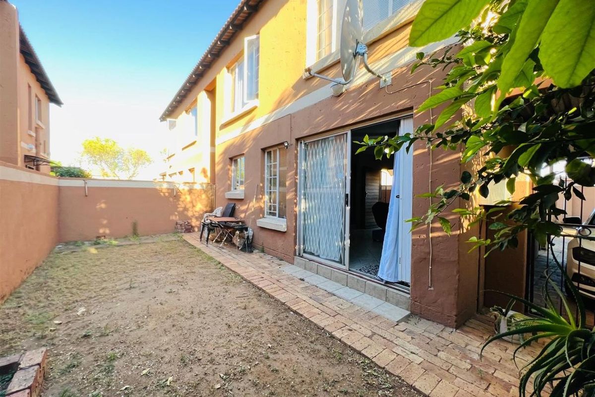 Rear view of the apartment featuring a private garden area, paved walkway, and sliding door access to the interior living space.