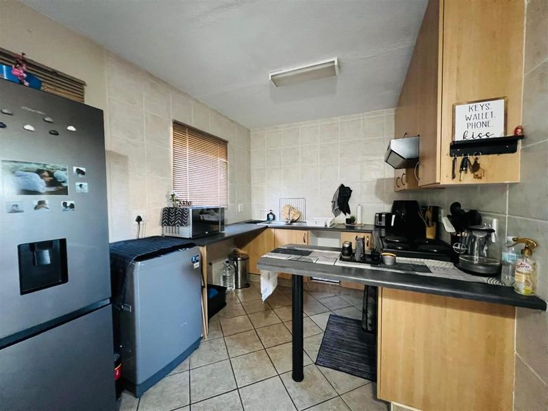 A functional kitchen featuring light wood cabinetry, tiled splashbacks, tiled flooring, and a built-in hob with extractor fan.