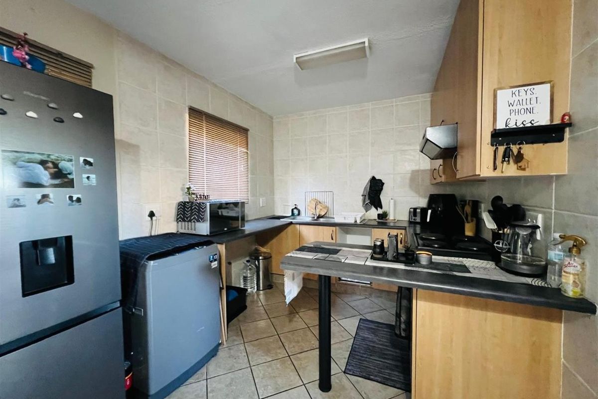 A functional kitchen featuring light wood cabinetry, tiled splashbacks, tiled flooring, and a built-in hob with extractor fan.